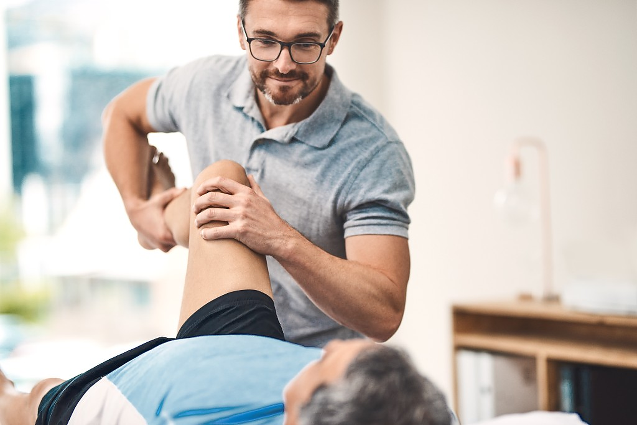 Physical therapist guiding a patient through a knee mobility exercise